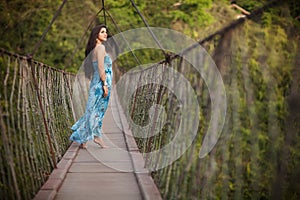 Beautiful girl on the suspended wooden bridge