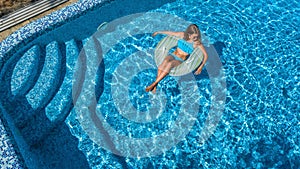 Beautiful girl in swimming pool aerial drone view from above, woman relaxes and swims on inflatable ring donut and has fun