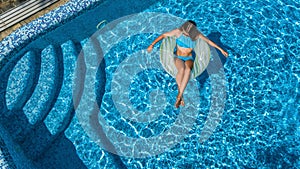 Beautiful girl in swimming pool aerial drone view from above, woman relaxes and swims on inflatable ring donut and has fun