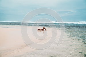 Beautiful girl in a swimsuit lies on the beach with white sand. model sunbathing on vacation near the ocean