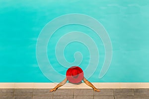 Beautiful girl in a swimsuit and a red hat in a blue water pool