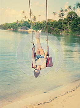 beautiful girl on a swing against the background tropical seascape