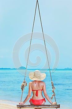 Beautiful girl is swinging at the sea background on a holiday.