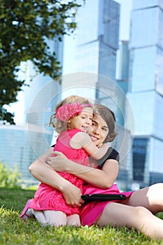 Beautiful girl with tablet pc hugs little girl on