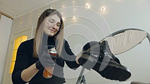 A beautiful girl takes care of shoes at home. Spraying shoes with a protective moisture-proof spray
