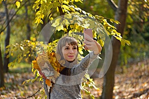 Beautiful girl takes pictures on the phone in the autumn park. Selfie. Wonder autumn. Lifestyle