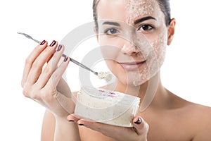 beautiful girl taking facial scrub from jar