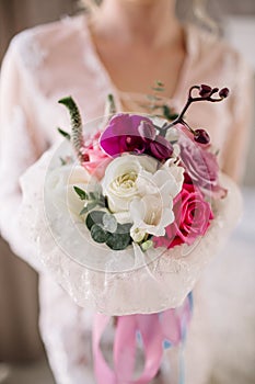 Beautiful girl in tender lacy dress with bouquet flowers peonies in hands standing against floral background in flower shop. Joyfu