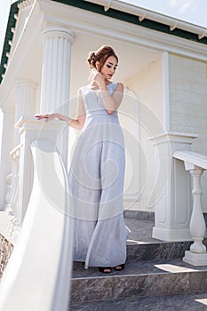 Beautiful girl in tender prom dress on stairs background. Female portrait