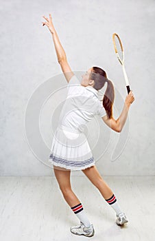 Beautiful girl in tennis clothes, brandishing a tennis racket on