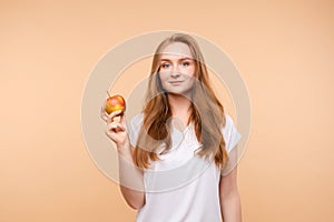 Beautiful girl with tied on back hair eating tasty apple.