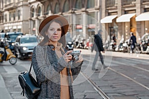 A beautiful girl tourist with a camera beautifully flutters her hair in the wind