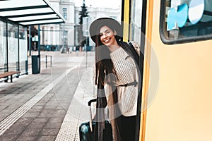 Beautiful girl tourist in coat and hat peek out of a tram door