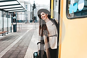 Beautiful girl tourist in coat and hat peek out of a tram door