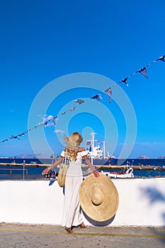 Beautiful girl tourist standing at Spetses marina seaport, Greece and looking at the sea