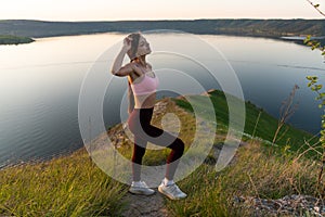 Beautiful girl tourist stands on top of a cliff and admires the beautiful landscape of the mountain with river range