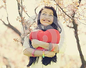 Beautiful girl with toy heart in spring park