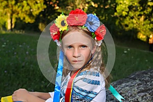 Beautiful girl in traditional Ukrainian clothes holding a flag of ukraine