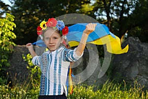 Beautiful girl in traditional Ukrainian clothes holding a flag of ukraine