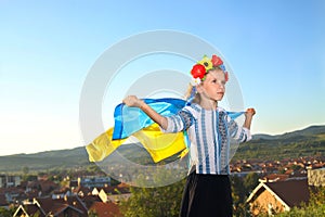 Beautiful girl in traditional Ukrainian clothes holding a flag of ukraine