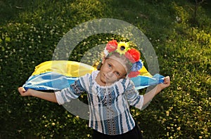 Beautiful girl in traditional Ukrainian clothes holding a flag of ukraine