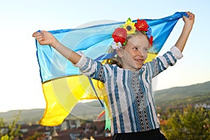 Beautiful girl in traditional Ukrainian clothes holding a flag of ukraine