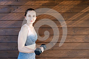Beautiful girl training outdoor. Sports girl in a sportswear. Girl holding dumbbells in her arms and doing workout