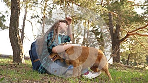 Beautiful girl travels with pet. tourist girl in forest on halt with a dog. mistress plays with hunting hound. mistress