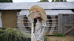 Beautiful girl with two braids in hat and romantic dress looking away on rural landscape in countryside. Countrygirl in