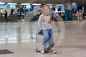 Beautiful girl with two pigtails with a suitcase on a journey from the airport