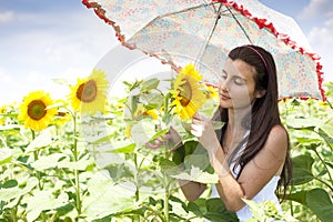 Beautiful girl with umbrella in a sunflower field