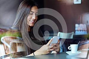 Beautiful girl using her mobile phone in cafe.