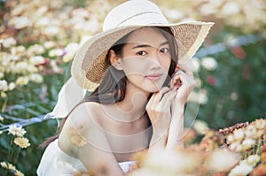 Beautiful girl in vintage dress and hat standing near colorful flowers