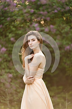 Beautiful girl in a vintage dress in spring lilac garden