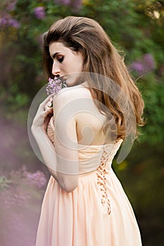 Beautiful girl in a vintage dress in spring lilac garden