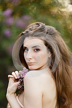 Beautiful girl in a vintage dress in spring lilac garden