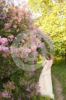 Beautiful girl in a vintage dress in spring lilac garden