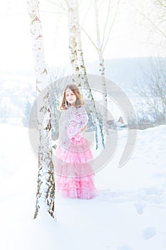 A beautiful girl walks on a frozen forest covered with snow