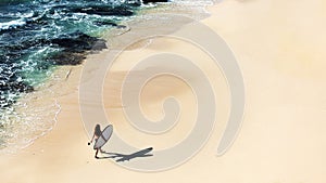 Beautiful girl walks with a surfboard on a wild beach