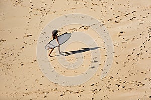 Beautiful girl walks with a surfboard on a wild beach
