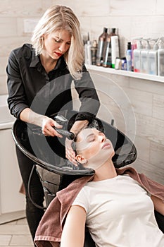 Beautiful girl washes her hair before a haircut in a beauty salon. hair washing at a hairdressing. professional shampoo
