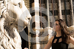 Beautiful girl wearing a black dress next to Gothic style lion statue