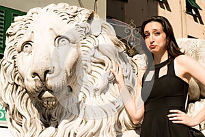 Beautiful girl wearing a black dress next to Gothic style lion statue