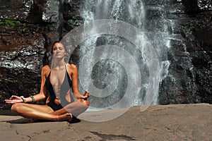 Beautiful girl wearing black one piece swimsuit meditating in lotus yoga pose