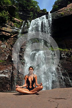 Beautiful girl wearing black one piece swimsuit meditating in lotus yoga pose