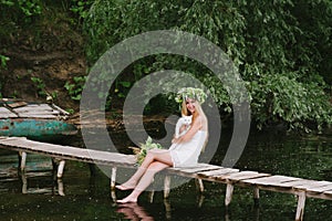 Beautiful girl wearing a crown sitting on a wooden bridge with a cat