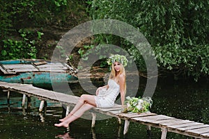 Beautiful girl wearing a crown sitting on a wooden bridge with a cat