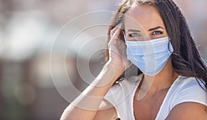 Beautiful girl wearing disposable facemask, looking into the camera during the coronavirus outbreak photo