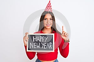 Beautiful girl wearing fanny party hat holding blackboard over isolated white background surprised with an idea or question