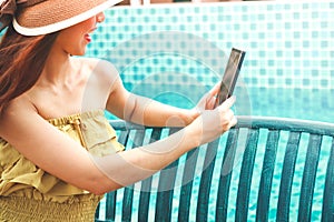 Beautiful girl wearing a hat, holding a phone, taking pictures at the pool